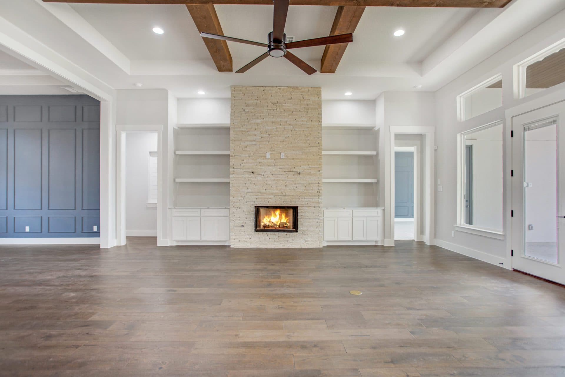 Custom great room with a beamed ceiling and stone fireplace in a JLP-built Hill Country home